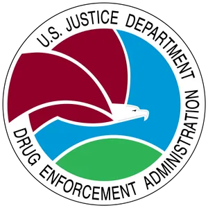 A circular badge that reads "U.S. Justice Department Drug Enforcement Administration" around the border in black capitals, with a red, blue, and green illustration of an eagle flying above a hill