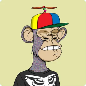 An ape with fur colored like television static wears a rainbow-colored hat with a propeller. Its eyes are closed, it's biting its lower lip, and it's wearing a black shirt with a skeleton printed on it.