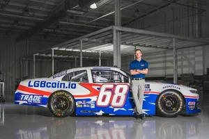 NASCAR driver poses standing against a racecar with American flag detailing, the domain "LGBcoin.io", and the number 68 painted on it