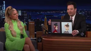 Paris Hilton, wearing a neon green dress, sits onstage next to Jimmy Fallon, who is at his desk on the Tonight Show. He is holding up two cardboard printouts of Bored Ape NFTs.