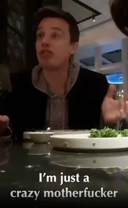 Kyle Roche sitting in a dim restaurant setting, speaking and gesturing. A caption on the video reads "I'm just a crazy motherfucker".