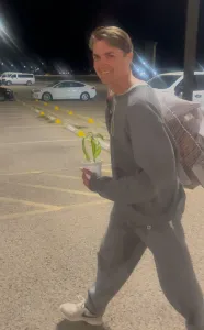 Ross Ulbricht leaving prison in January 2025, wearing a grey sweatsuit and carrying a small potted plant